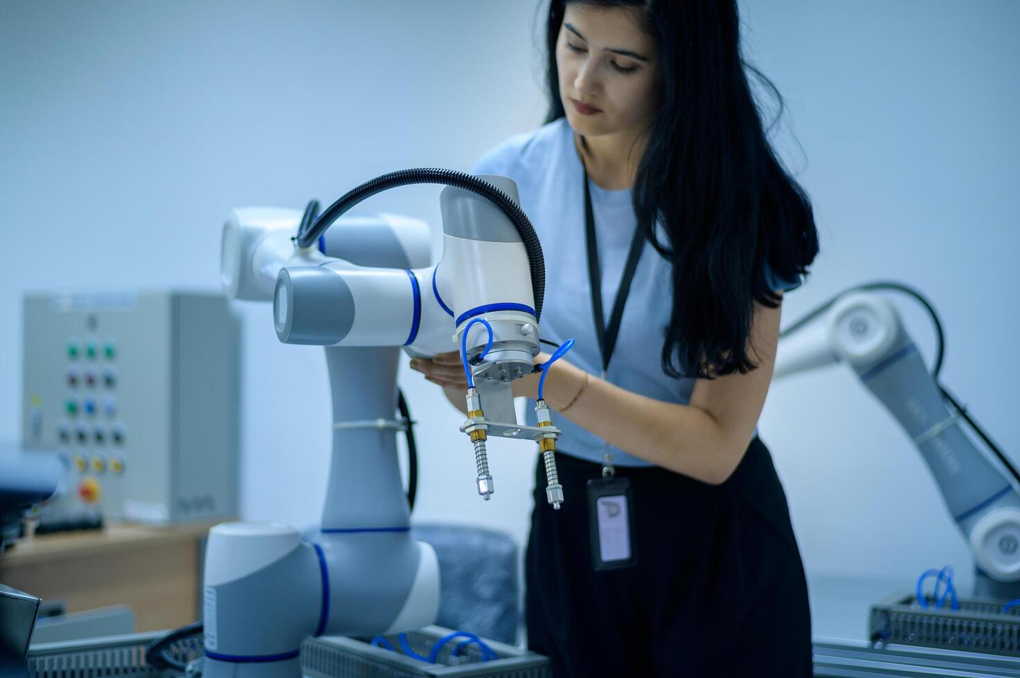 Female Robotics engineer working with Programming and Manipulating Robot Hand, Industrial Robotics Design, High Tech Facility, Modern Machine Learning. Mass Production Automatics. photo