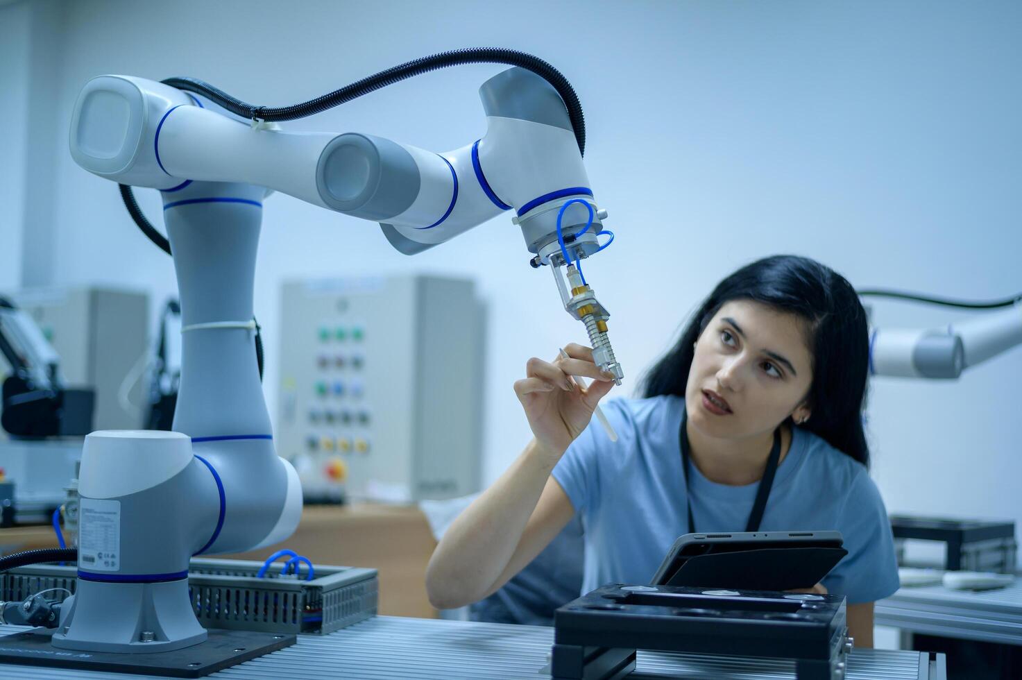 Female Robotics engineer working with Programming and Manipulating Robot Hand, Industrial Robotics Design, High Tech Facility, Modern Machine Learning. Mass Production Automatics. photo