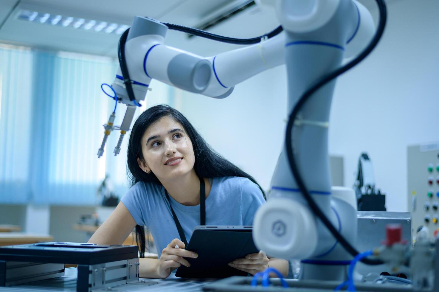 Female Robotics engineer working with Programming and Manipulating Robot Hand, Industrial Robotics Design, High Tech Facility, Modern Machine Learning. Mass Production Automatics. photo