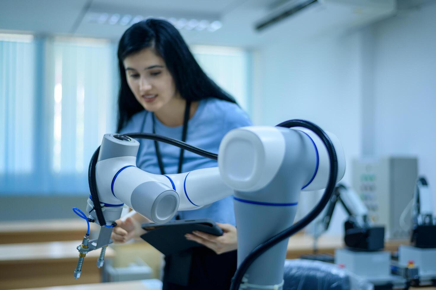 Female Robotics engineer working with Programming and Manipulating Robot Hand, Industrial Robotics Design, High Tech Facility, Modern Machine Learning. Mass Production Automatics. photo