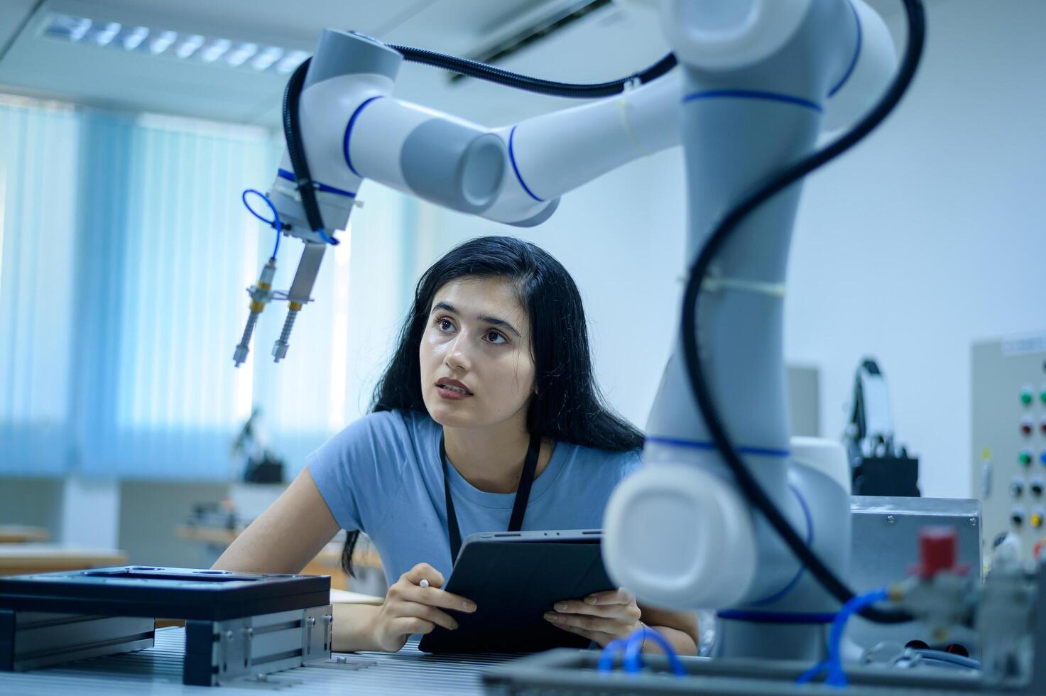 Female Robotics engineer working with Programming and Manipulating Robot Hand, Industrial Robotics Design, High Tech Facility, Modern Machine Learning. Mass Production Automatics. photo