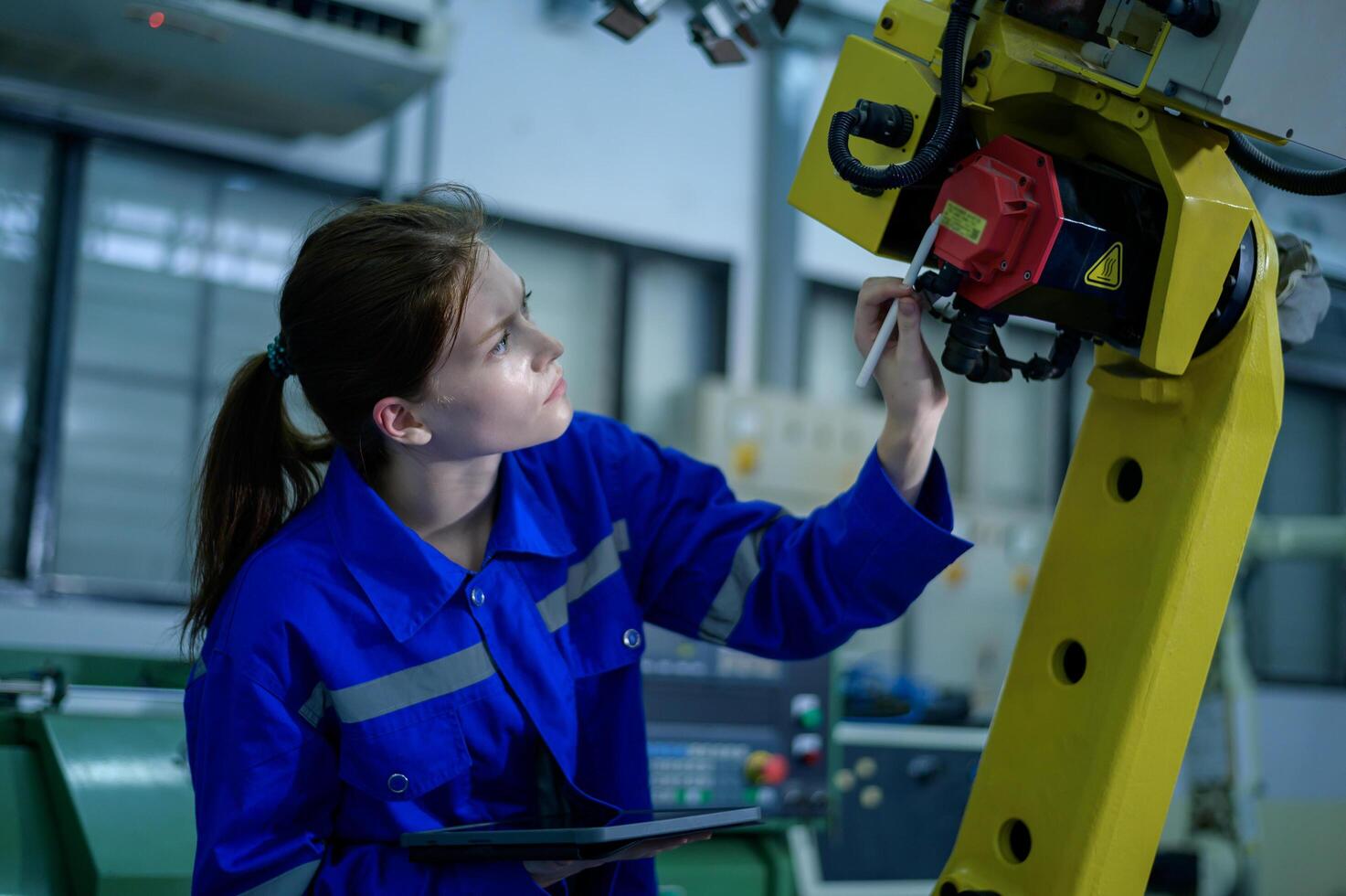 Female Robotics engineer working with Programming and Manipulating Robot Hand, Industrial Robotics Design, High Tech Facility, Modern Machine Learning. Mass Production Automatics. photo