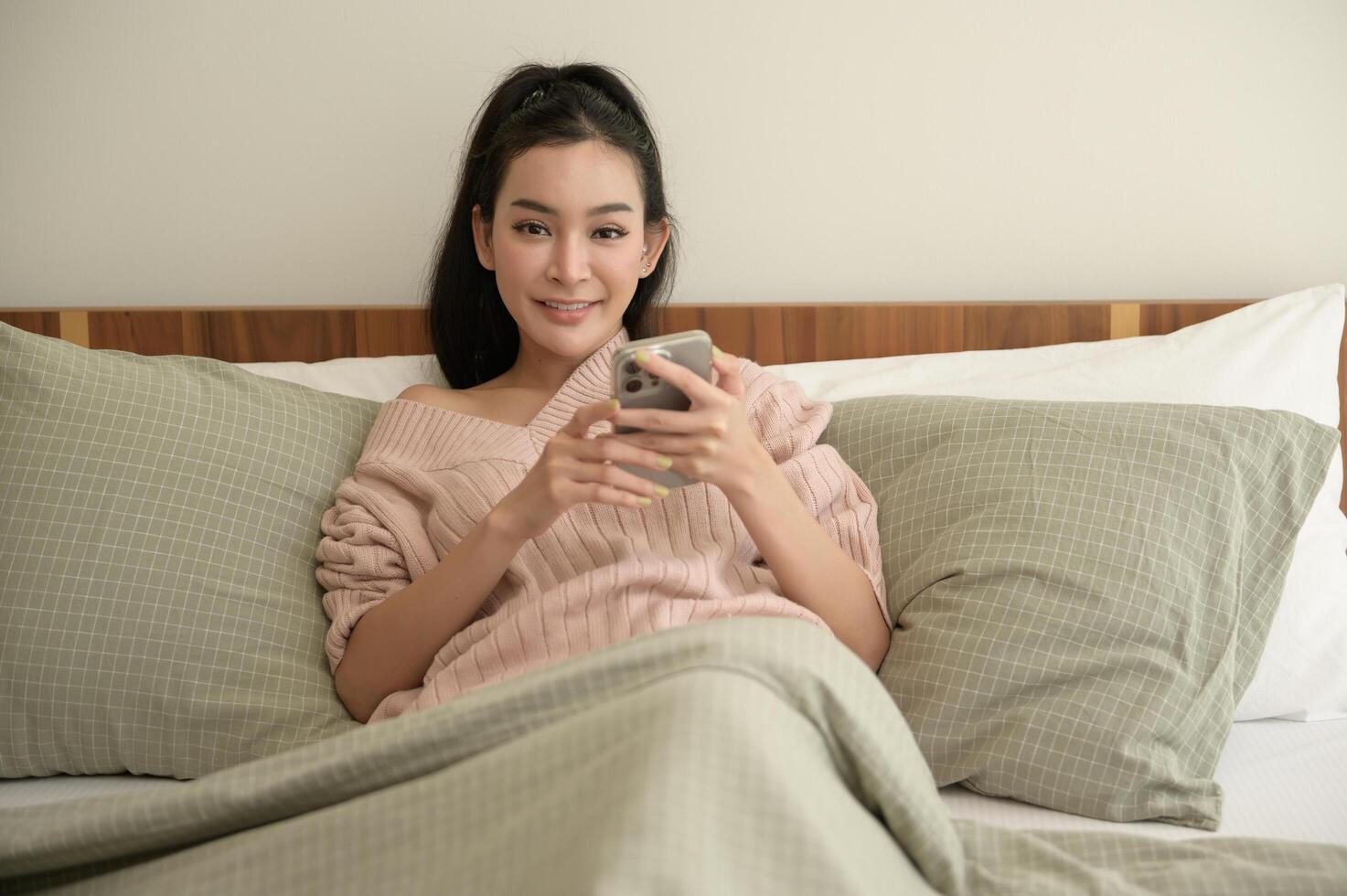 Young asian woman using smart phone lying on bed photo