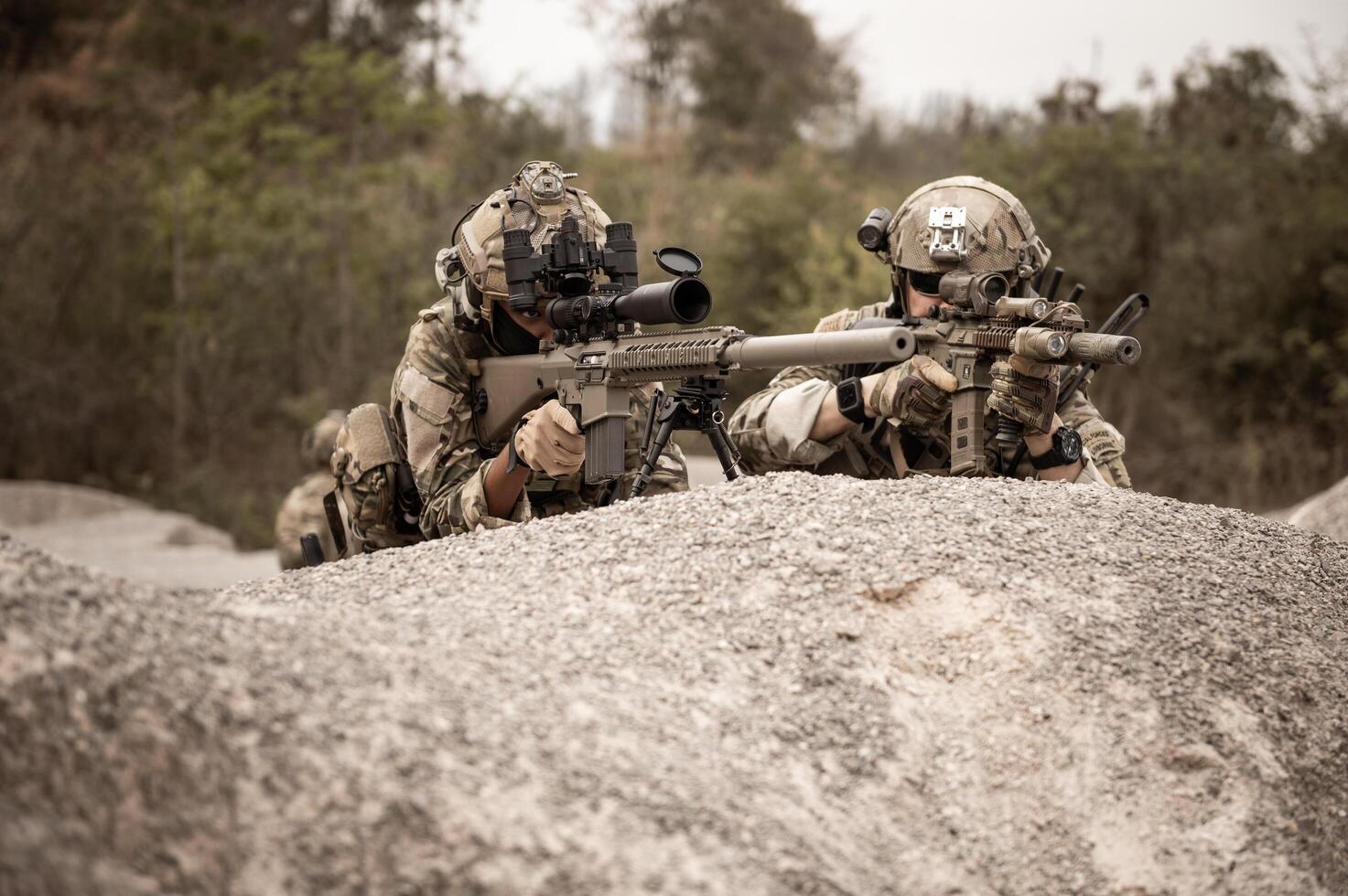 Soldiers in camouflage uniforms aiming with their riflesready to fire during military operation in the desert soldiers training  in a military operation photo