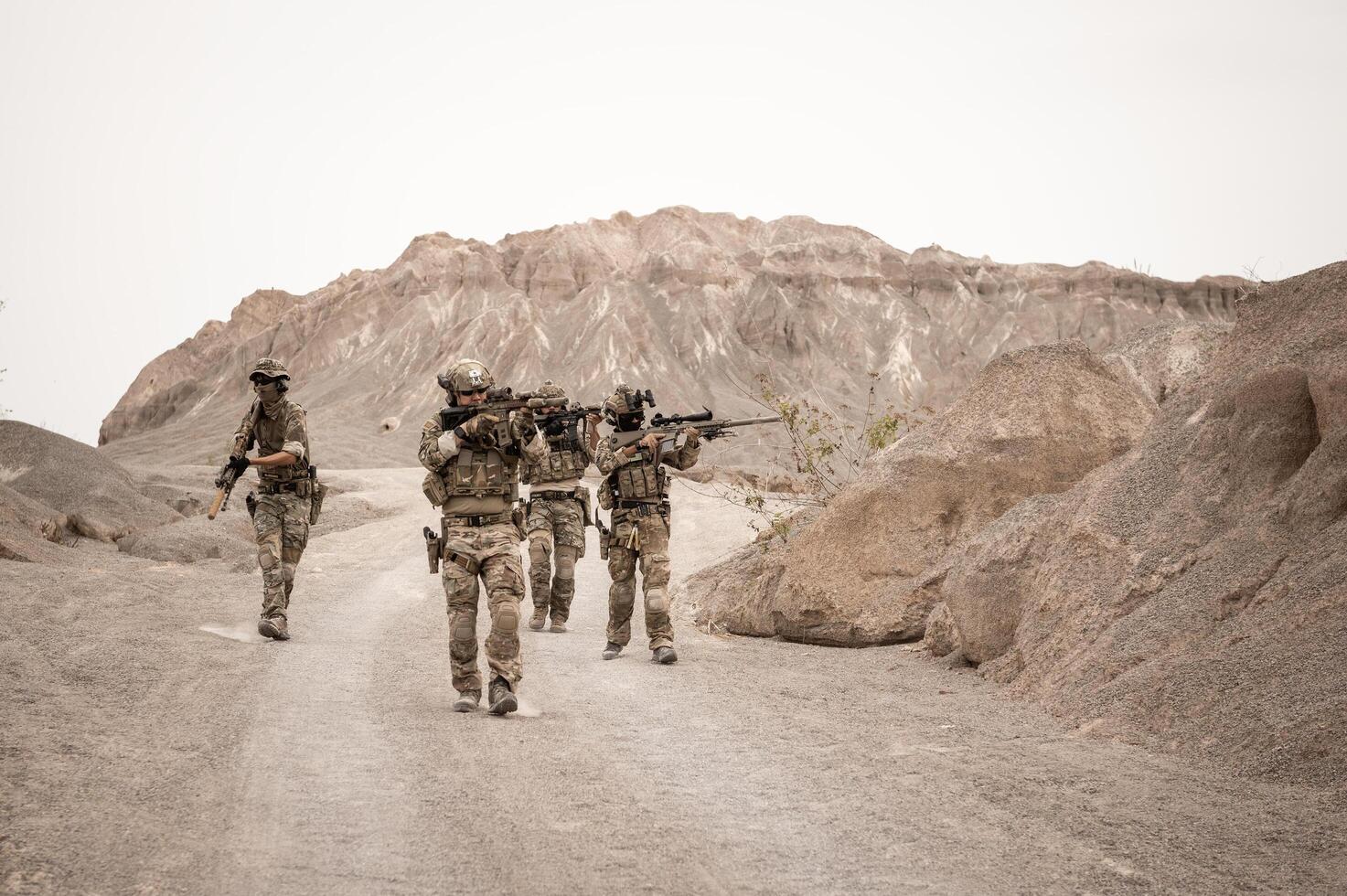 Soldiers in camouflage uniforms aiming with their riflesready to fire during military operation in the desert soldiers training  in a military operation photo