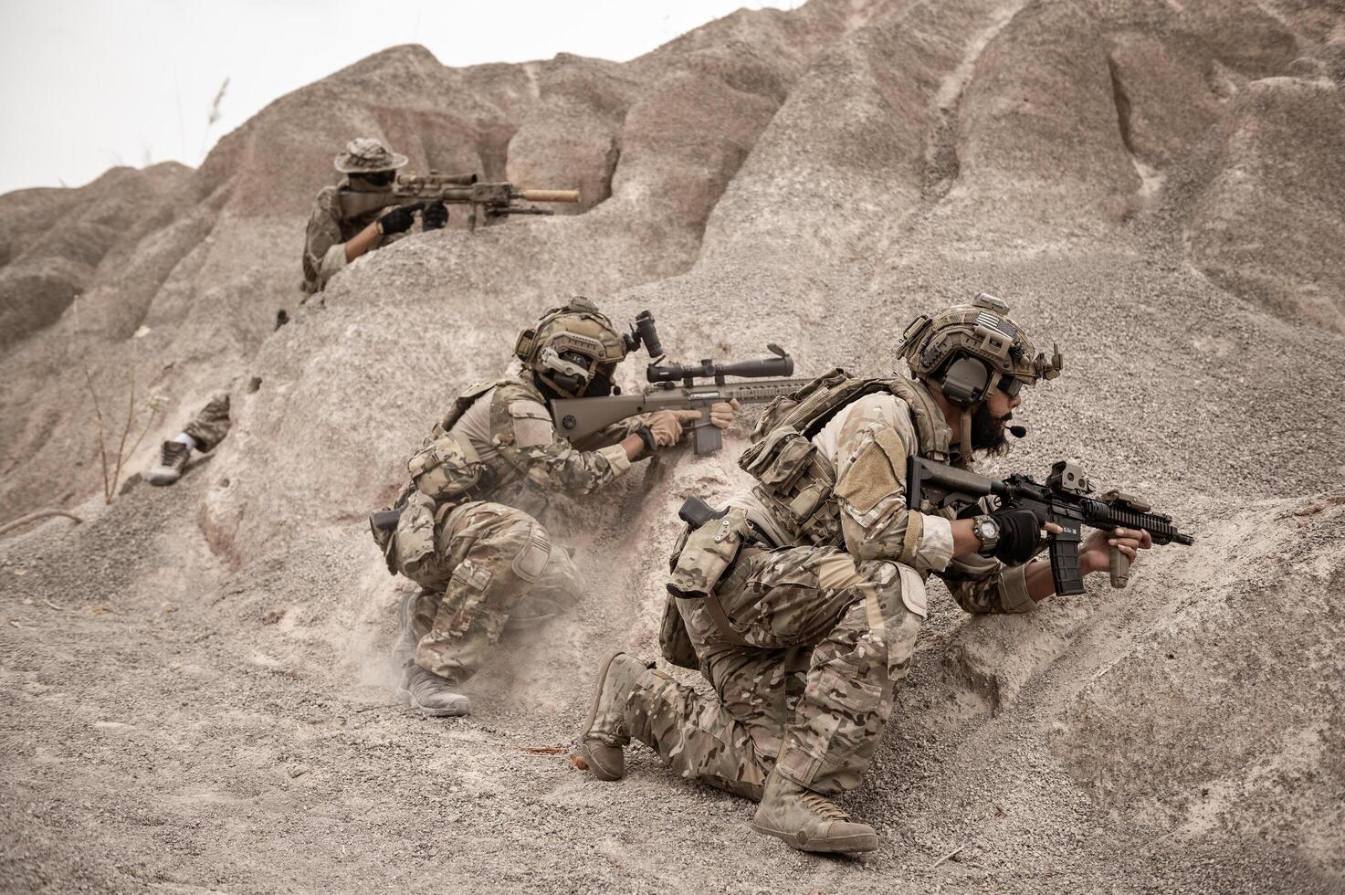 Soldiers in camouflage uniforms aiming with their riflesready to fire during military operation in the desert soldiers training  in a military operation photo