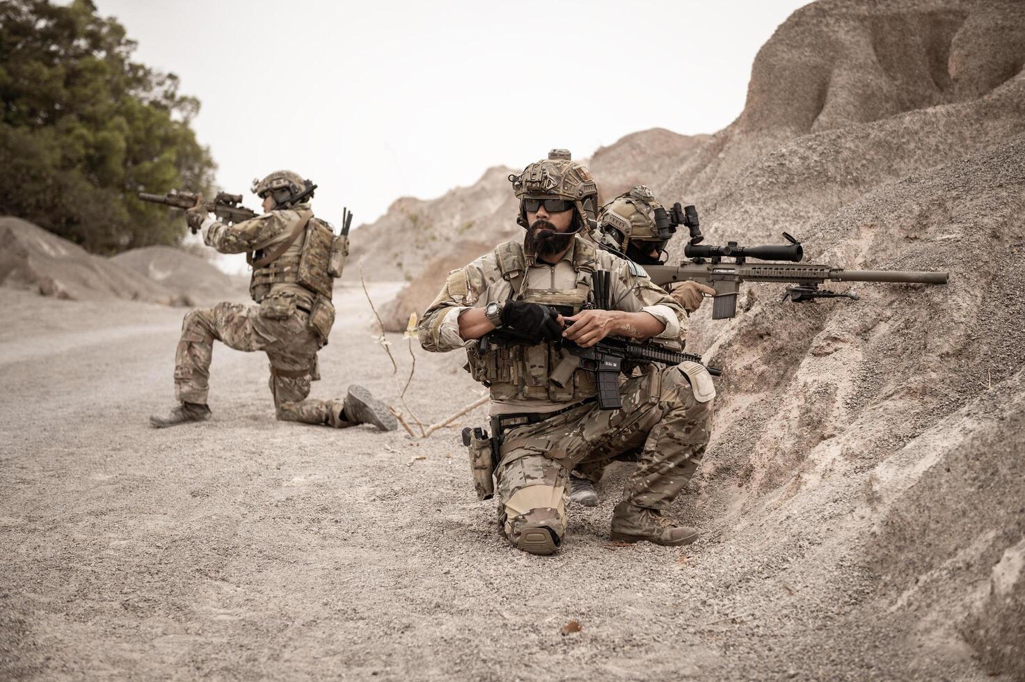 Soldiers in camouflage uniforms aiming with their riflesready to fire during military operation in the desert soldiers training  in a military operation photo