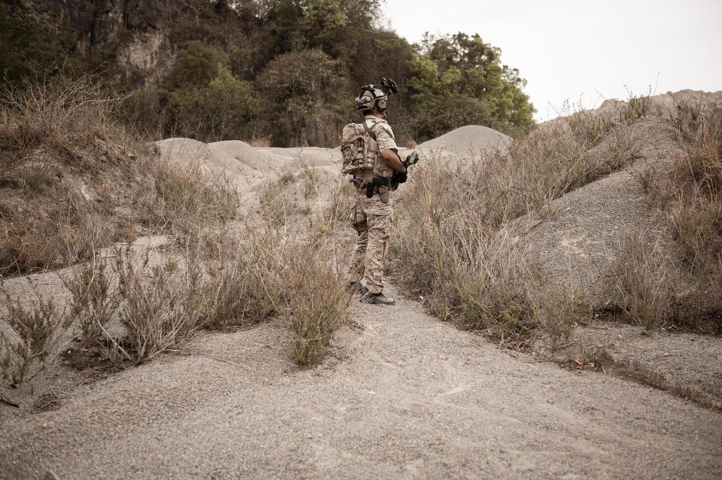 Soldiers in camouflage uniforms aiming with their riflesready to fire during military operation in the desert soldiers training  in a military operation photo