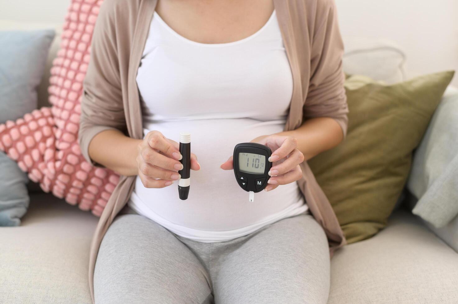 Pregnant woman checking blood sugar level by using Digital Glucose meter, health care, medicine, diabetes, glycemia concept photo