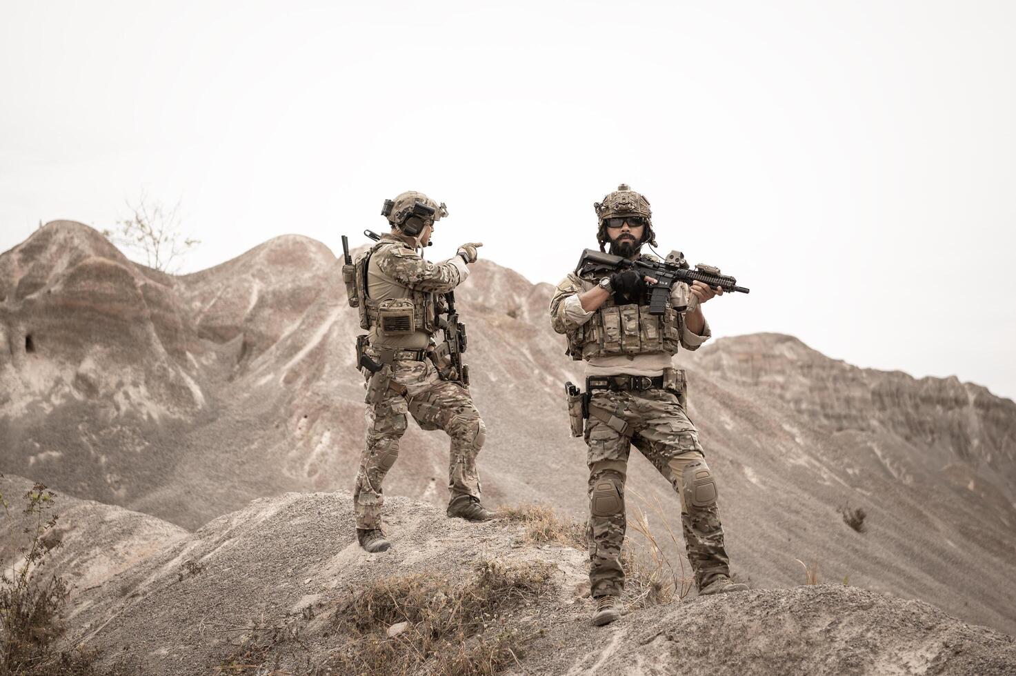 Soldiers in camouflage uniforms aiming with their riflesready to fire during military operation in the desert soldiers training  in a military operation photo