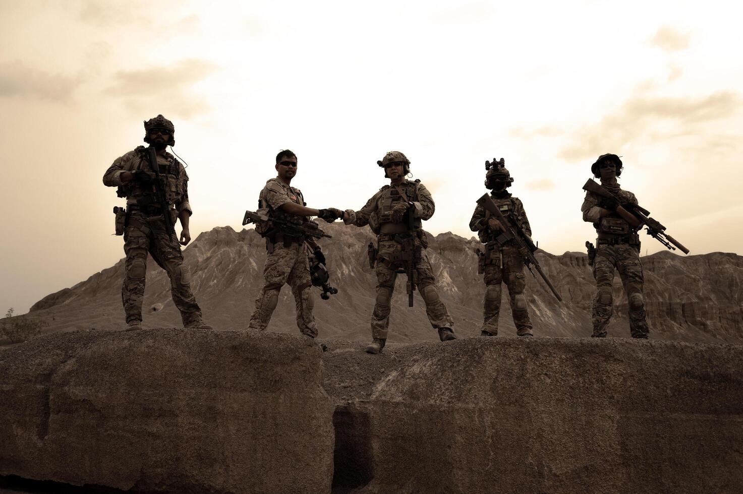 Soldiers in camouflage uniforms aiming with their riflesready to fire during military operation in the desert soldiers training  in a military operation photo