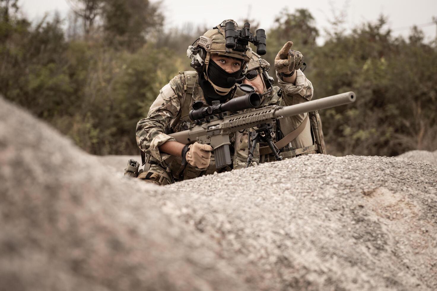 Soldiers in camouflage uniforms aiming with their riflesready to fire during military operation in the desert soldiers training  in a military operation photo