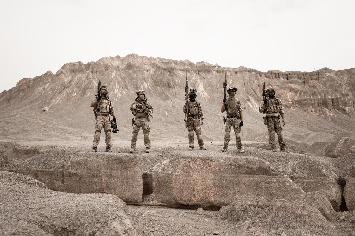 Soldiers in camouflage uniforms aiming with their riflesready to fire during military operation in the desert soldiers training  in a military operation photo