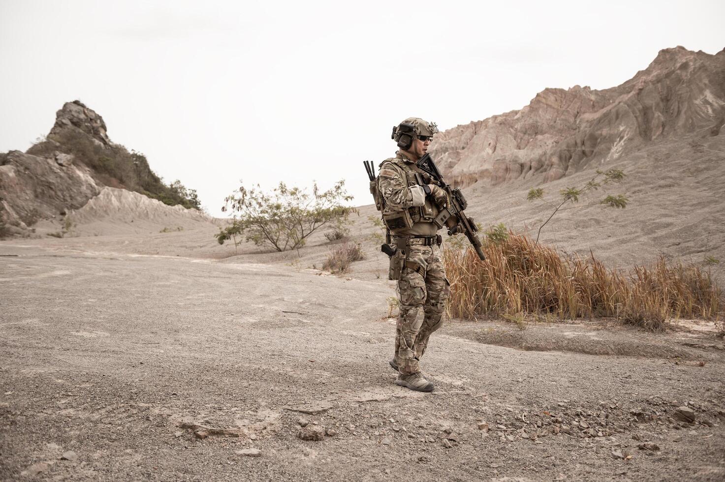 Soldiers in camouflage uniforms aiming with their riflesready to fire during military operation in the desert soldiers training  in a military operation photo