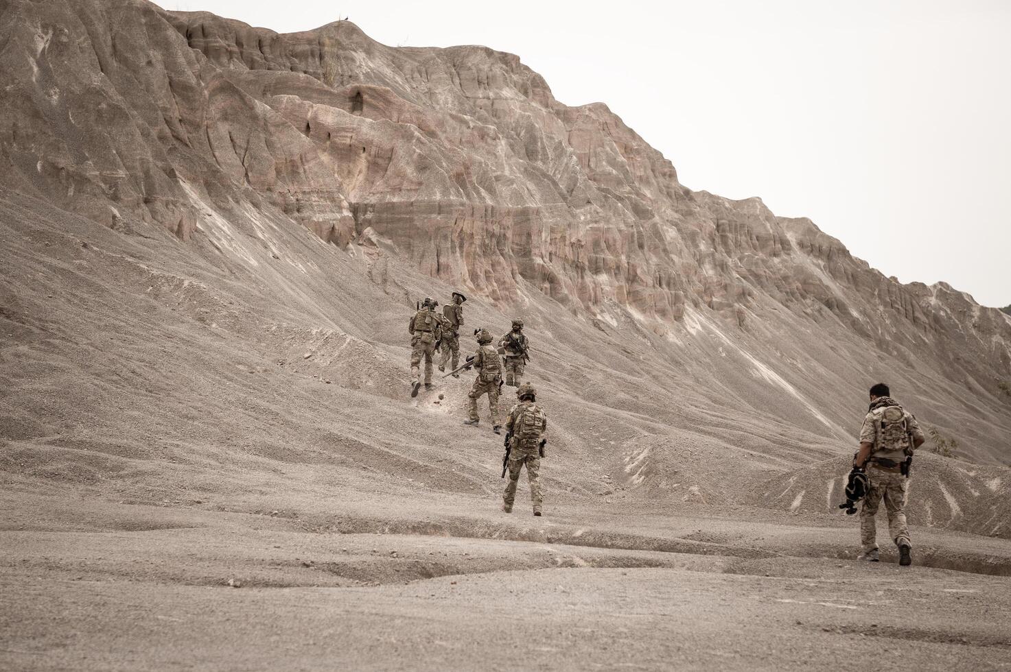 Soldiers in camouflage uniforms aiming with their riflesready to fire during military operation in the desert soldiers training  in a military operation photo