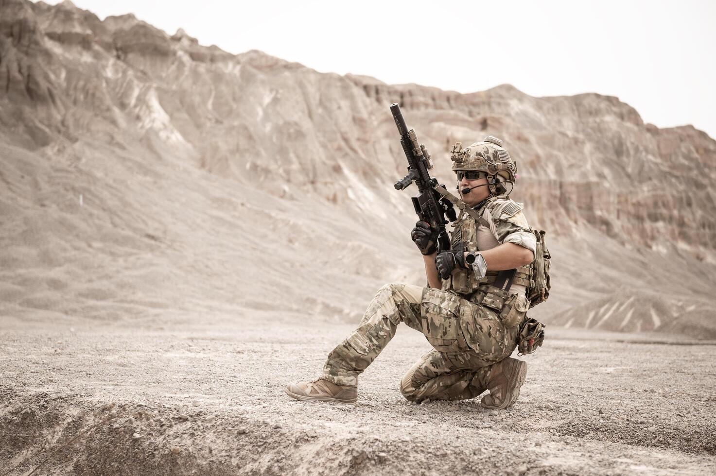 Soldiers in camouflage uniforms aiming with their riflesready to fire during military operation in the desert soldiers training  in a military operation photo