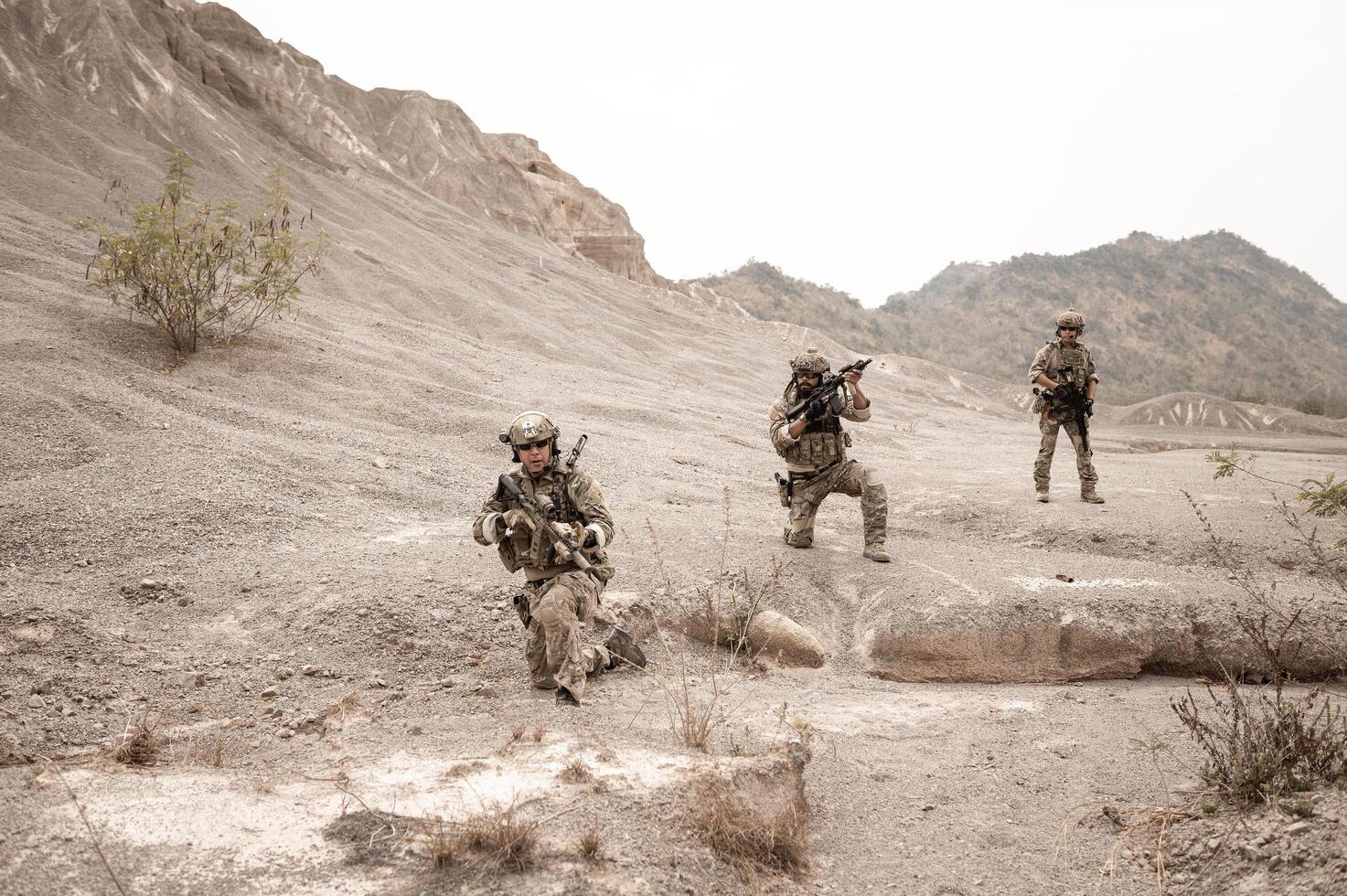 Soldiers in camouflage uniforms aiming with their riflesready to fire during military operation in the desert soldiers training  in a military operation photo