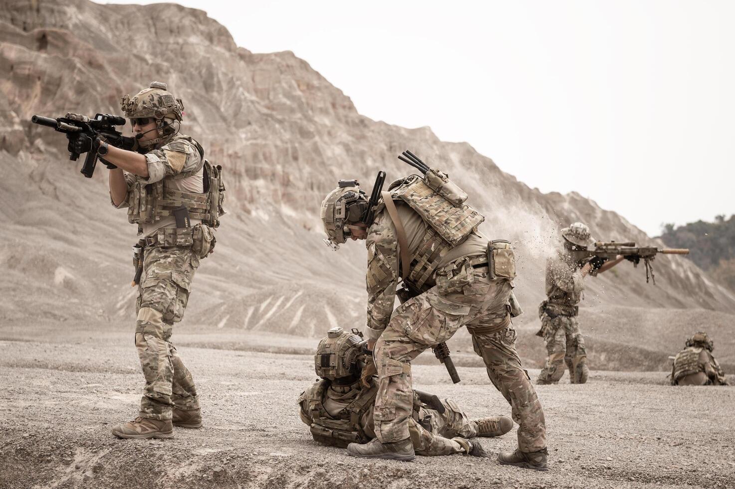 Soldiers in camouflage uniforms aiming with their riflesready to fire during military operation in the desert soldiers training  in a military operation photo