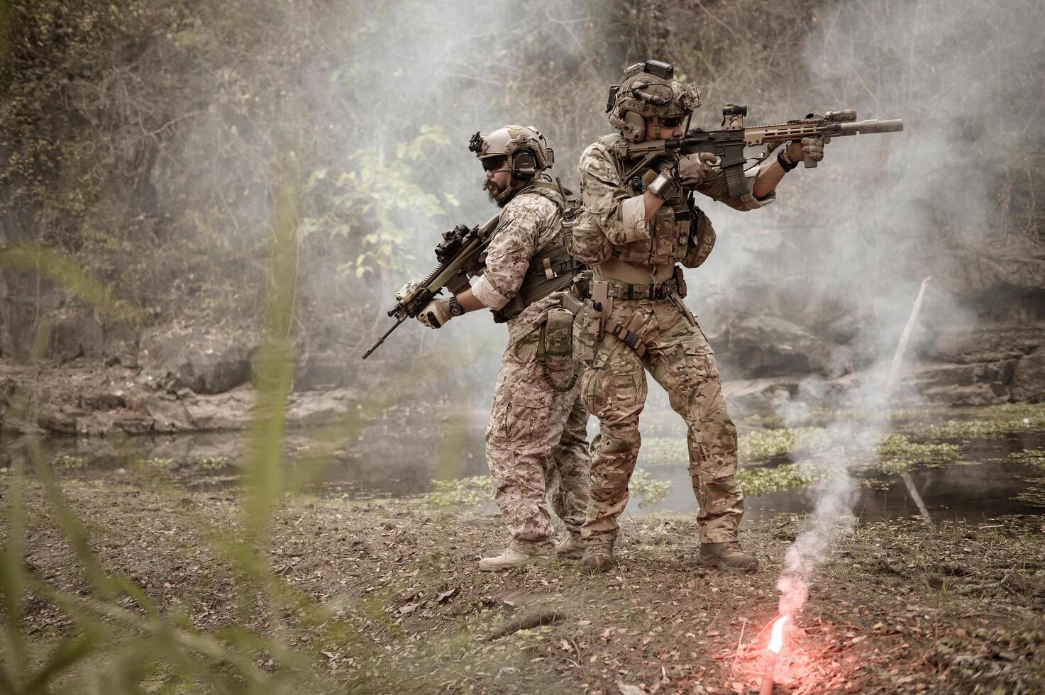 Soldiers  in camouflage uniforms aiming with their riflesready to fire during Military Operation in the forest soldiers training  in a military operation photo