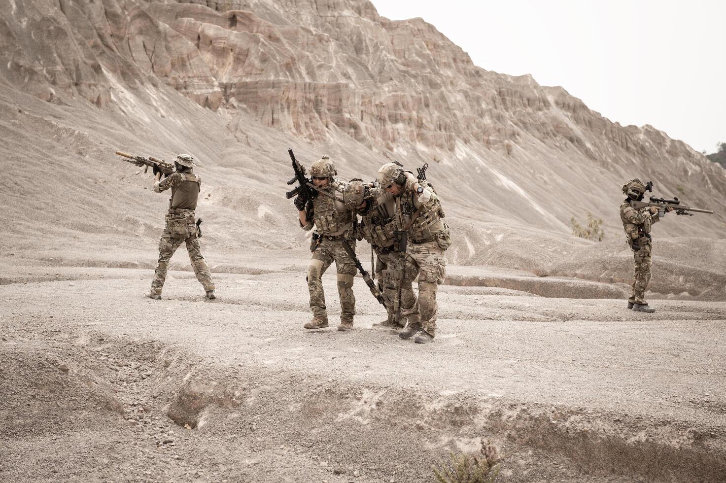 Soldiers in camouflage uniforms aiming with their riflesready to fire during military operation in the desert soldiers training  in a military operation photo