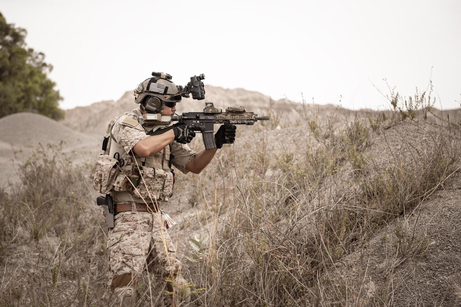 Soldiers in camouflage uniforms aiming with their riflesready to fire during military operation in the desert soldiers training  in a military operation photo
