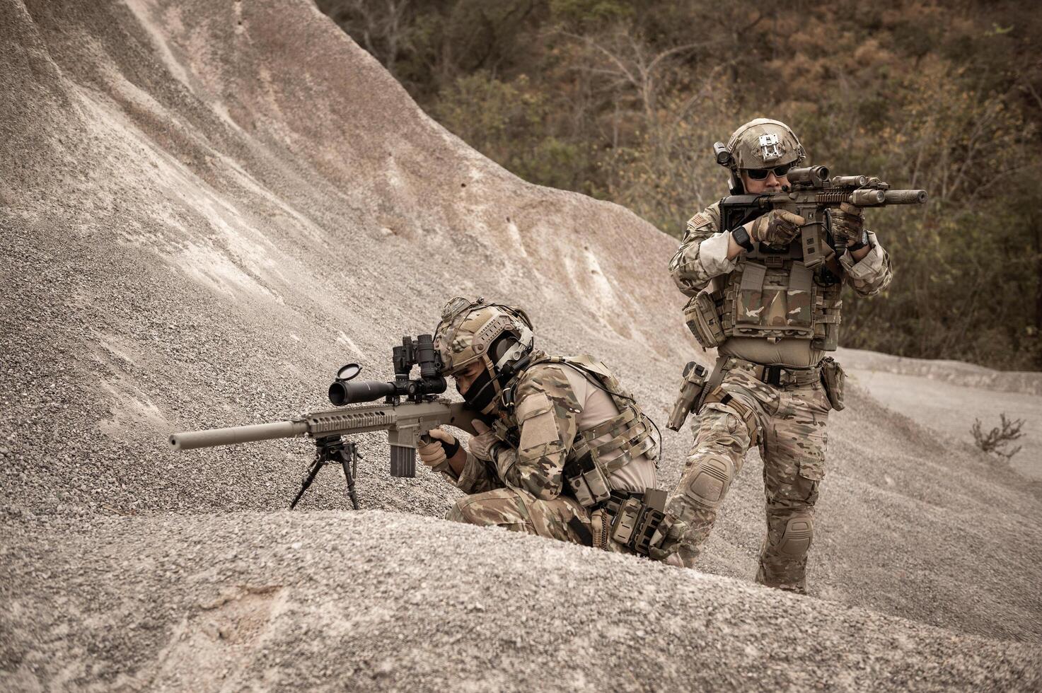 Soldiers in camouflage uniforms aiming with their riflesready to fire during military operation in the desert soldiers training  in a military operation photo