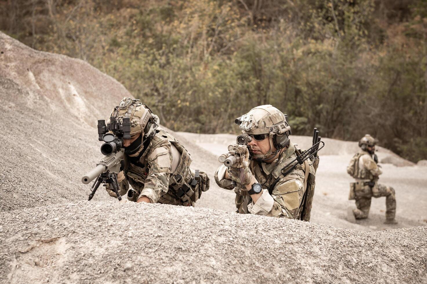 Soldiers in camouflage uniforms aiming with their riflesready to fire during military operation in the desert soldiers training  in a military operation photo