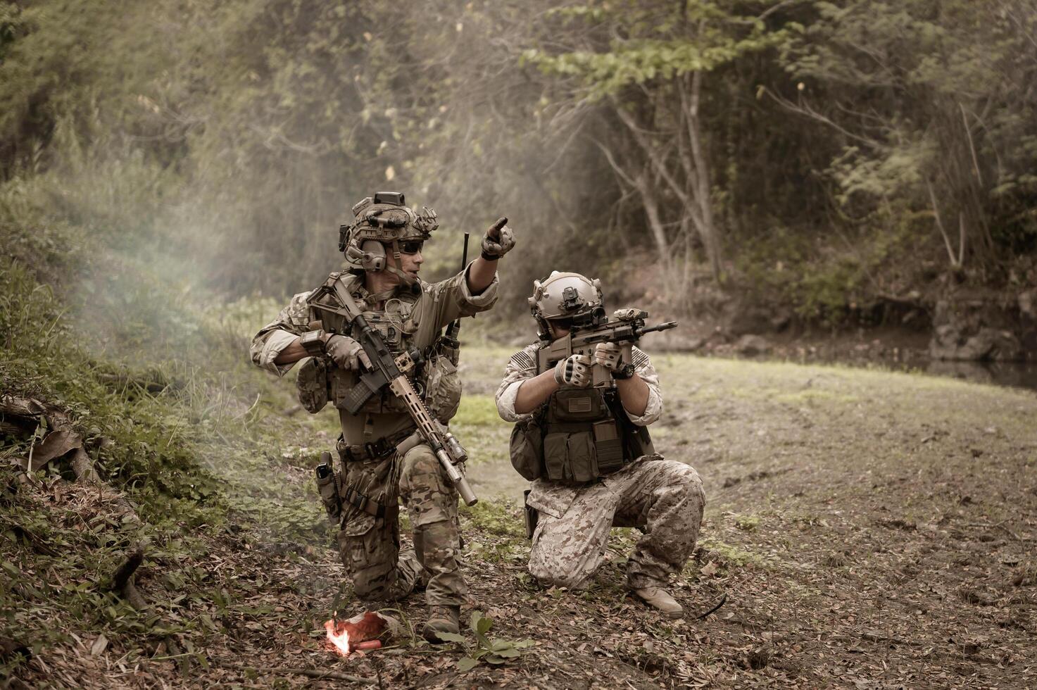 Soldiers  in camouflage uniforms aiming with their riflesready to fire during Military Operation in the forest soldiers training  in a military operation photo