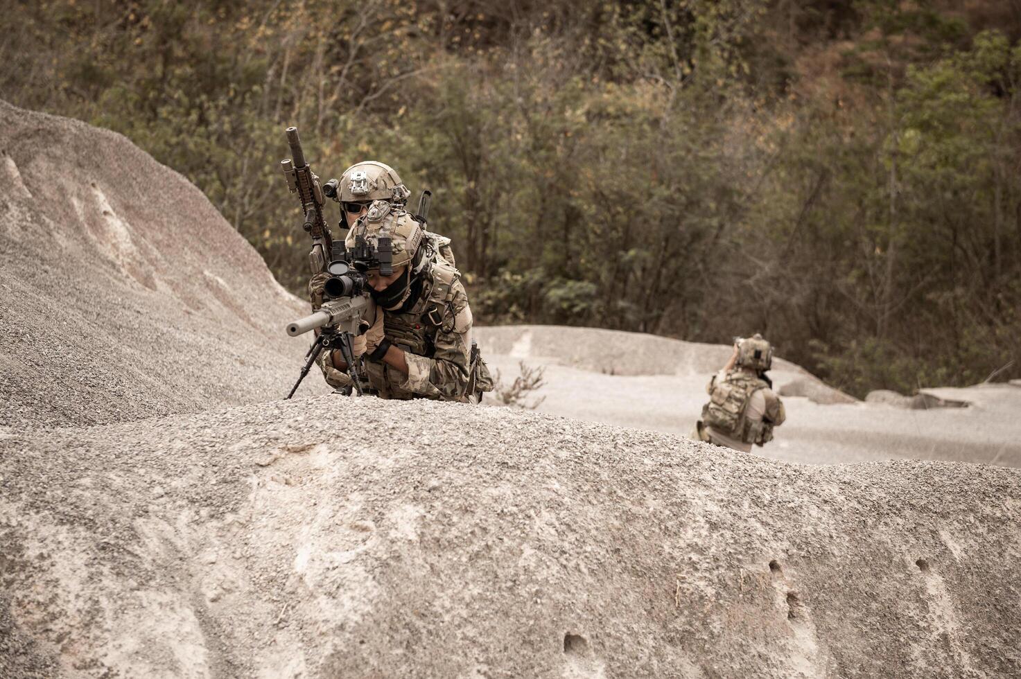 Soldiers in camouflage uniforms aiming with their riflesready to fire during military operation in the desert soldiers training  in a military operation photo