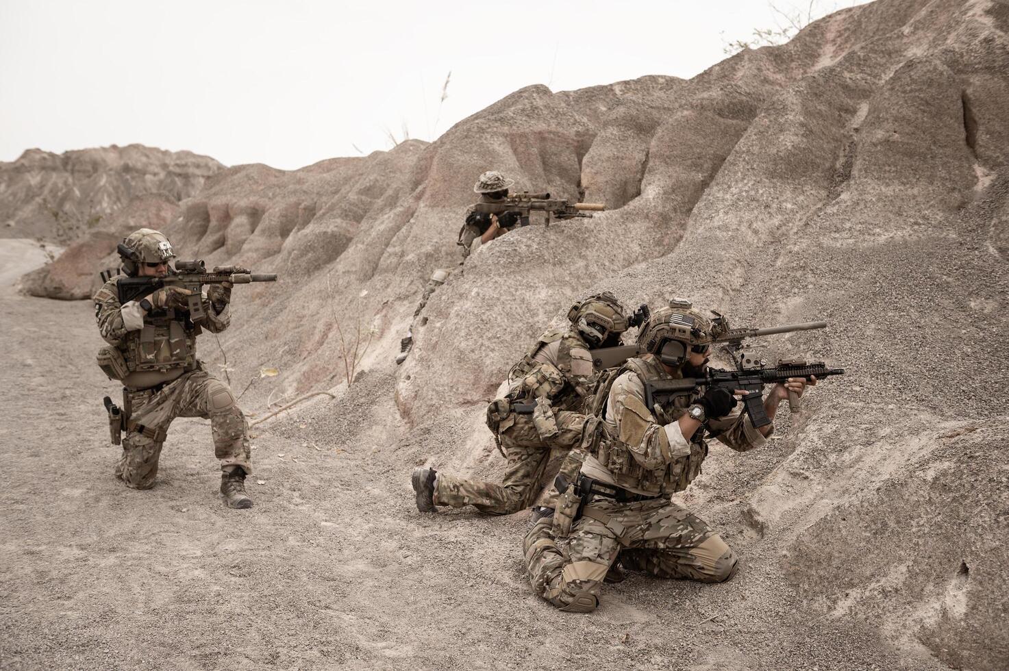 Soldiers in camouflage uniforms aiming with their riflesready to fire during military operation in the desert soldiers training  in a military operation photo