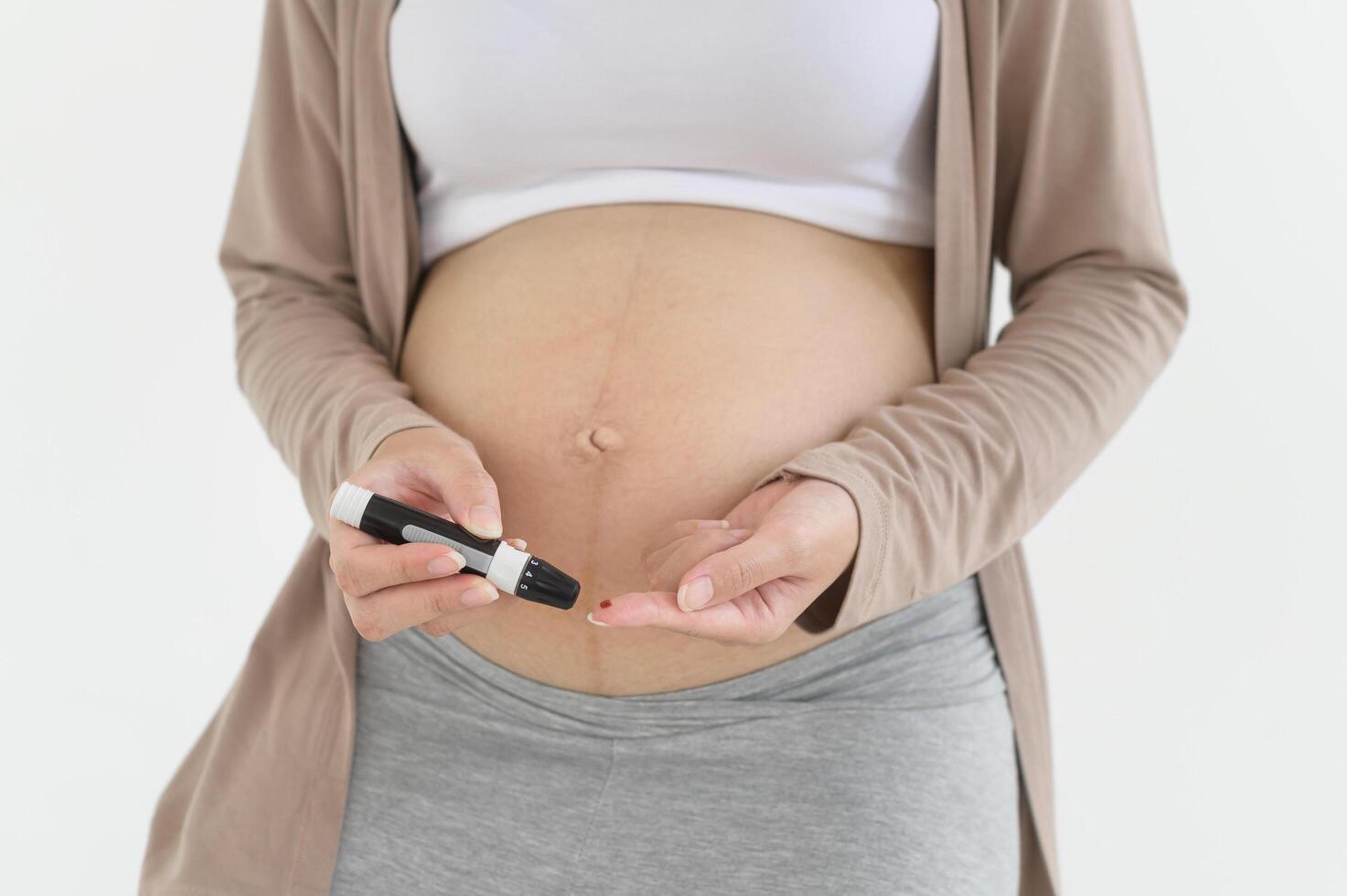 Pregnant woman checking blood sugar level by using Digital Glucose meter, health care, medicine, diabetes, glycemia concept photo