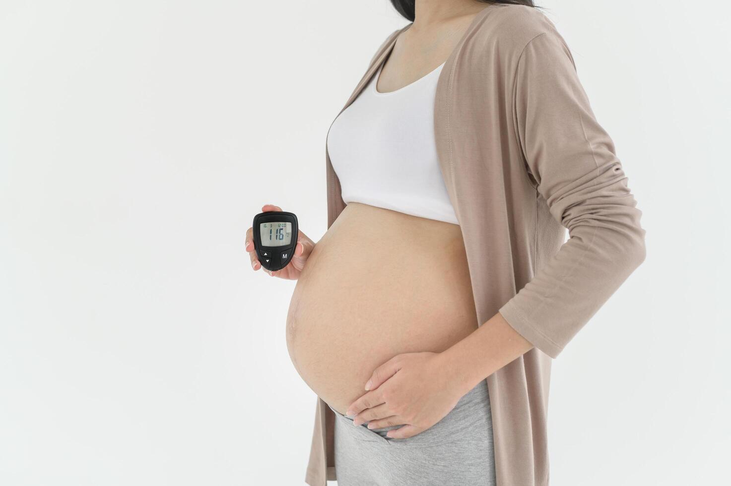 Pregnant woman checking blood sugar level by using Digital Glucose meter, health care, medicine, diabetes, glycemia concept photo