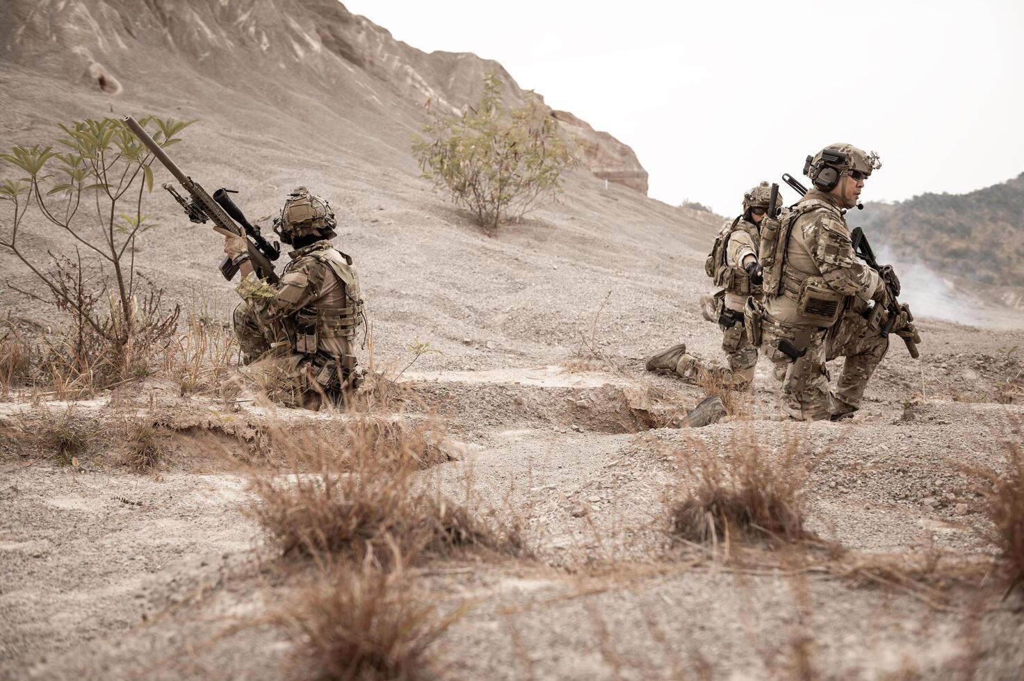 Soldiers in camouflage uniforms aiming with their riflesready to fire during military operation in the desert soldiers training in a military operation photo