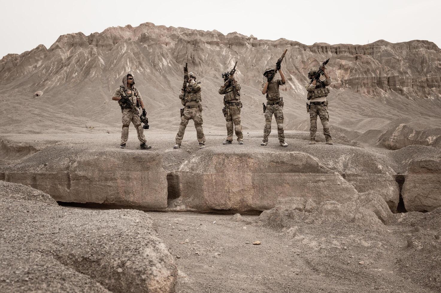 Soldiers in camouflage uniforms aiming with their riflesready to fire during military operation in the desert soldiers training in a military operation photo