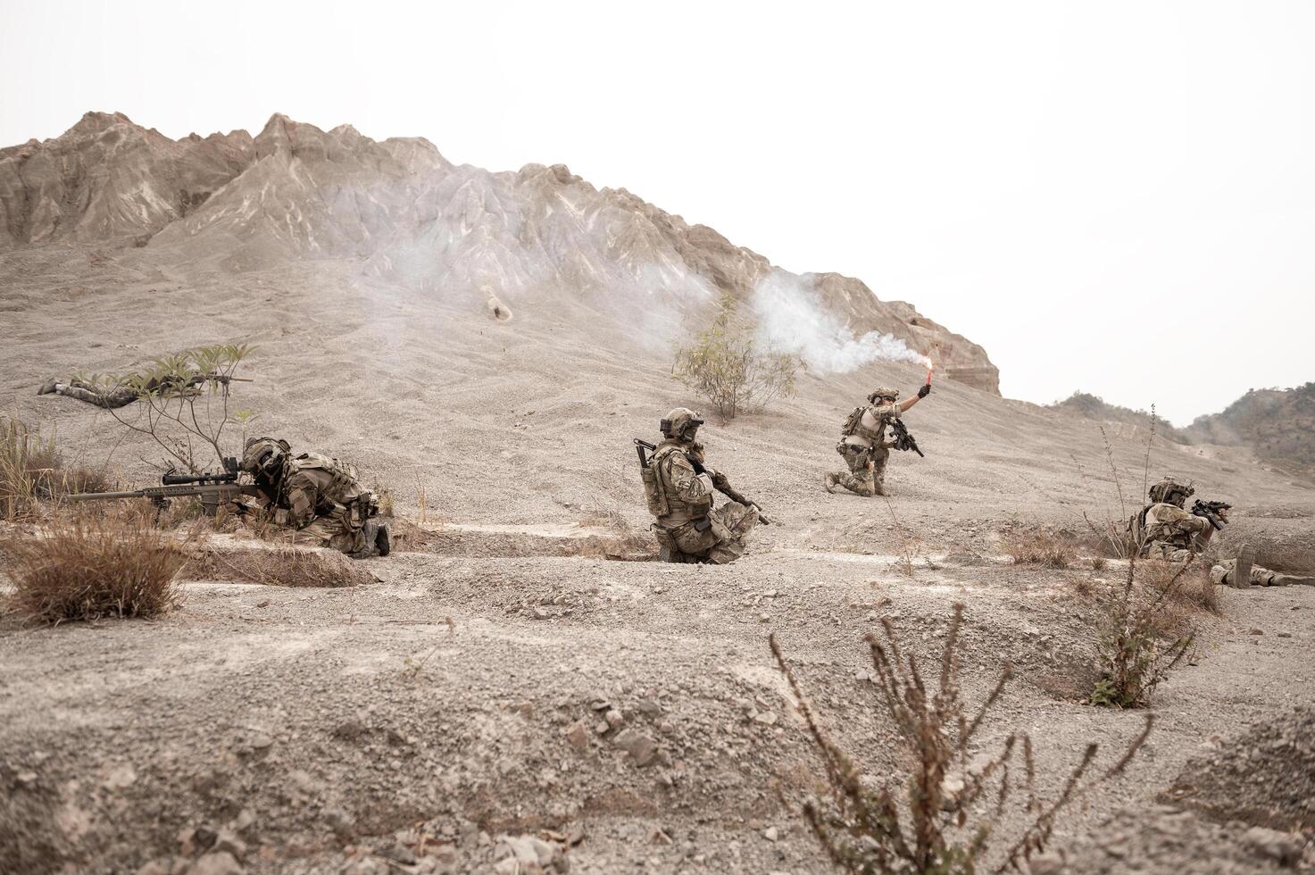 Soldiers in camouflage uniforms aiming with their riflesready to fire during military operation in the desert soldiers training in a military operation photo