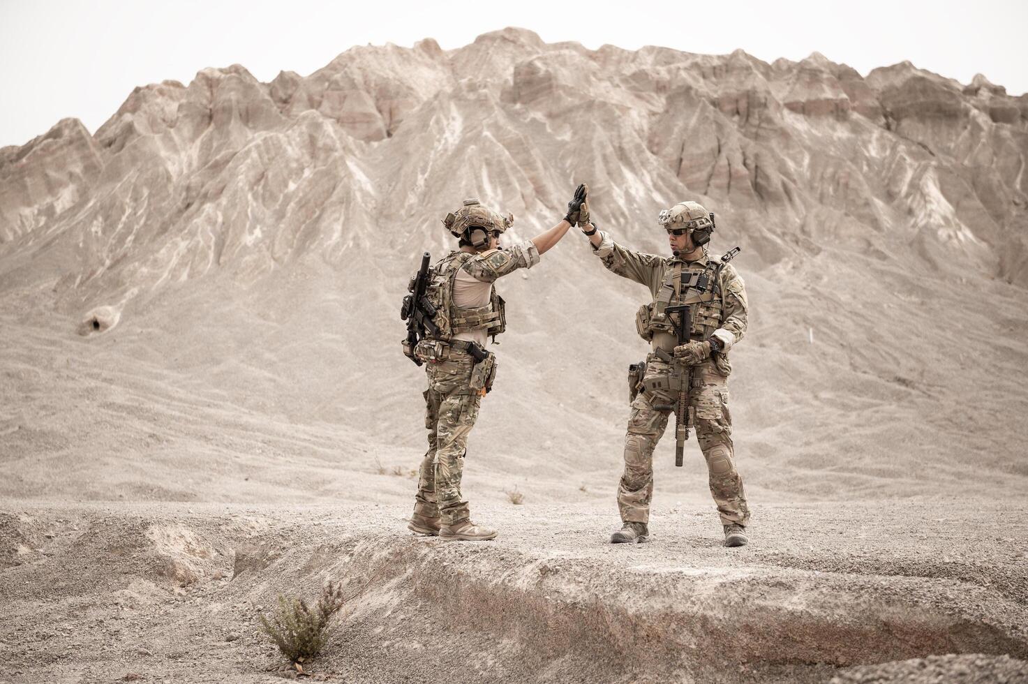 Soldiers in camouflage uniforms aiming with their riflesready to fire during military operation in the desert soldiers training in a military operation photo