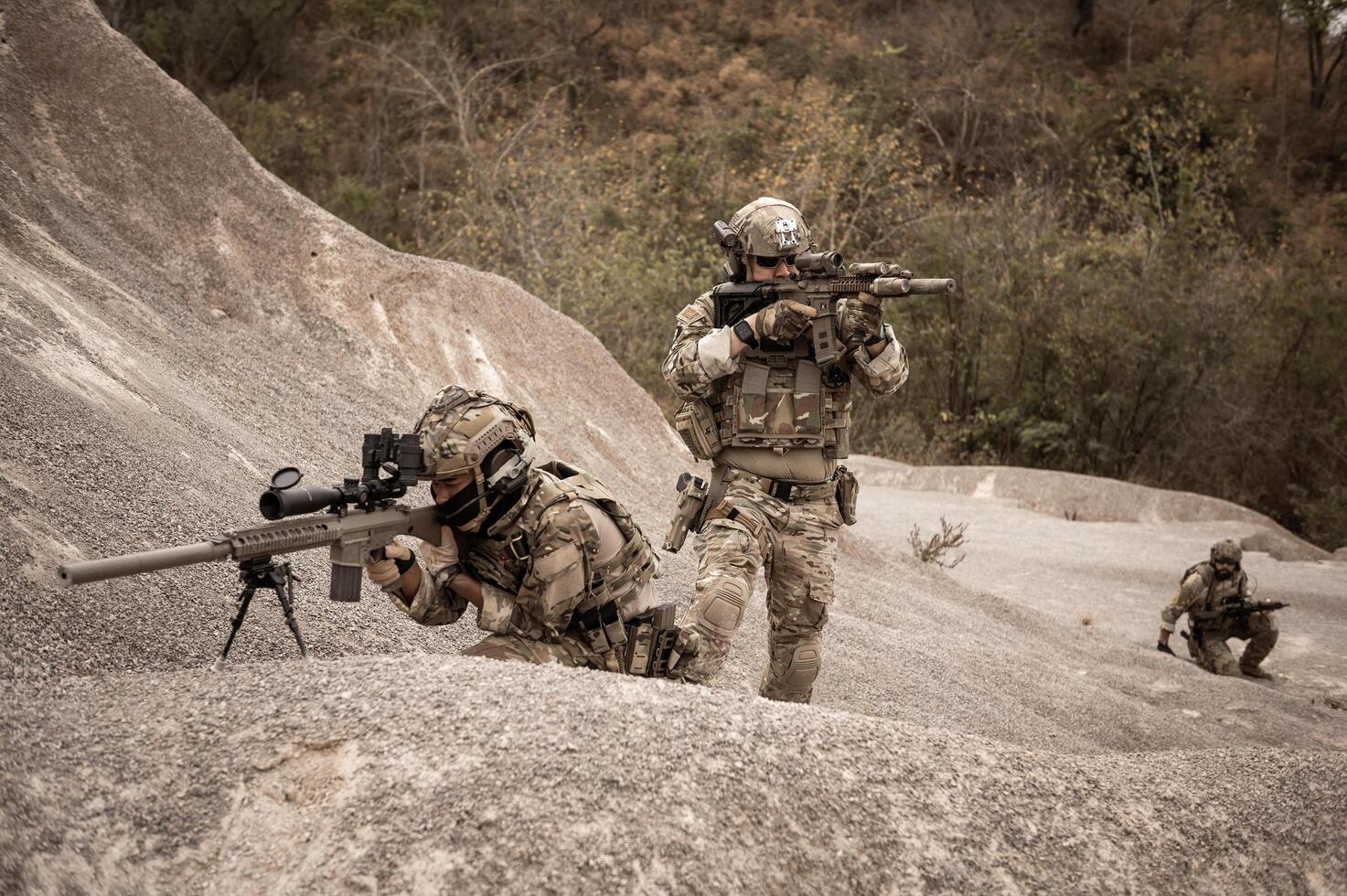 Soldiers in camouflage uniforms aiming with their riflesready to fire during military operation in the desert soldiers training in a military operation photo