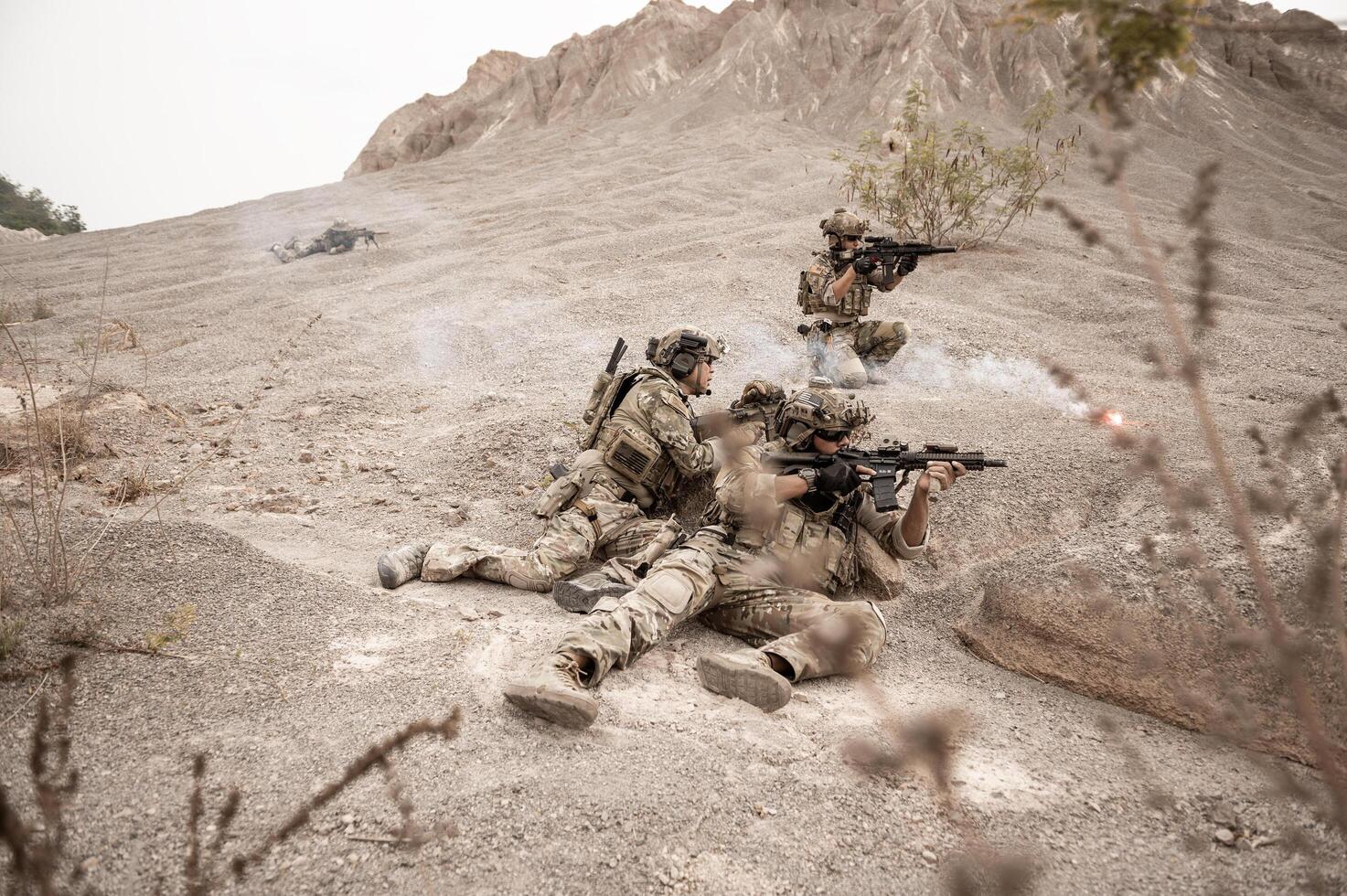 Soldiers in camouflage uniforms aiming with their riflesready to fire during military operation in the desert soldiers training in a military operation photo