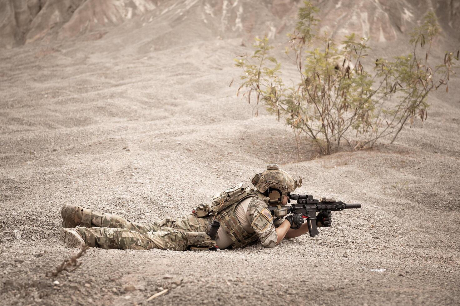 Soldiers in camouflage uniforms aiming with their riflesready to fire during military operation in the desert soldiers training in a military operation photo