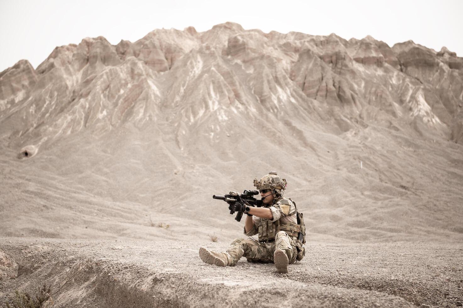 Soldiers in camouflage uniforms aiming with their riflesready to fire during military operation in the desert soldiers training in a military operation photo