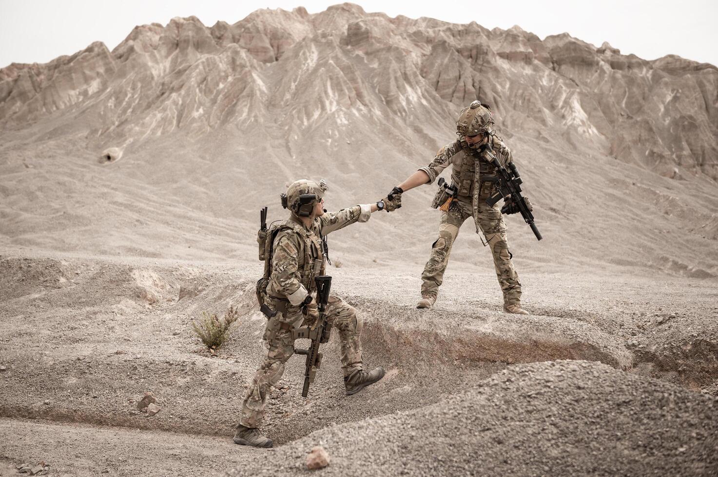 Soldiers in camouflage uniforms aiming with their riflesready to fire during military operation in the desert soldiers training in a military operation photo