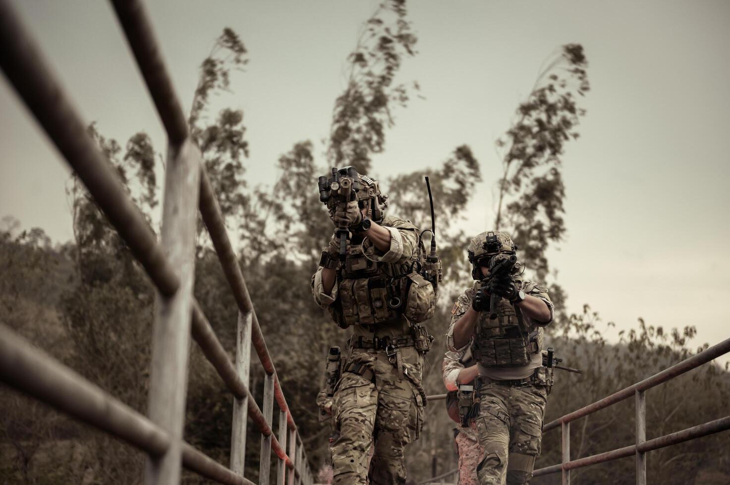 Soldiers in camouflage uniforms aiming with their riflesready to fire during Military Operation in the forest soldiers training in a military operation photo