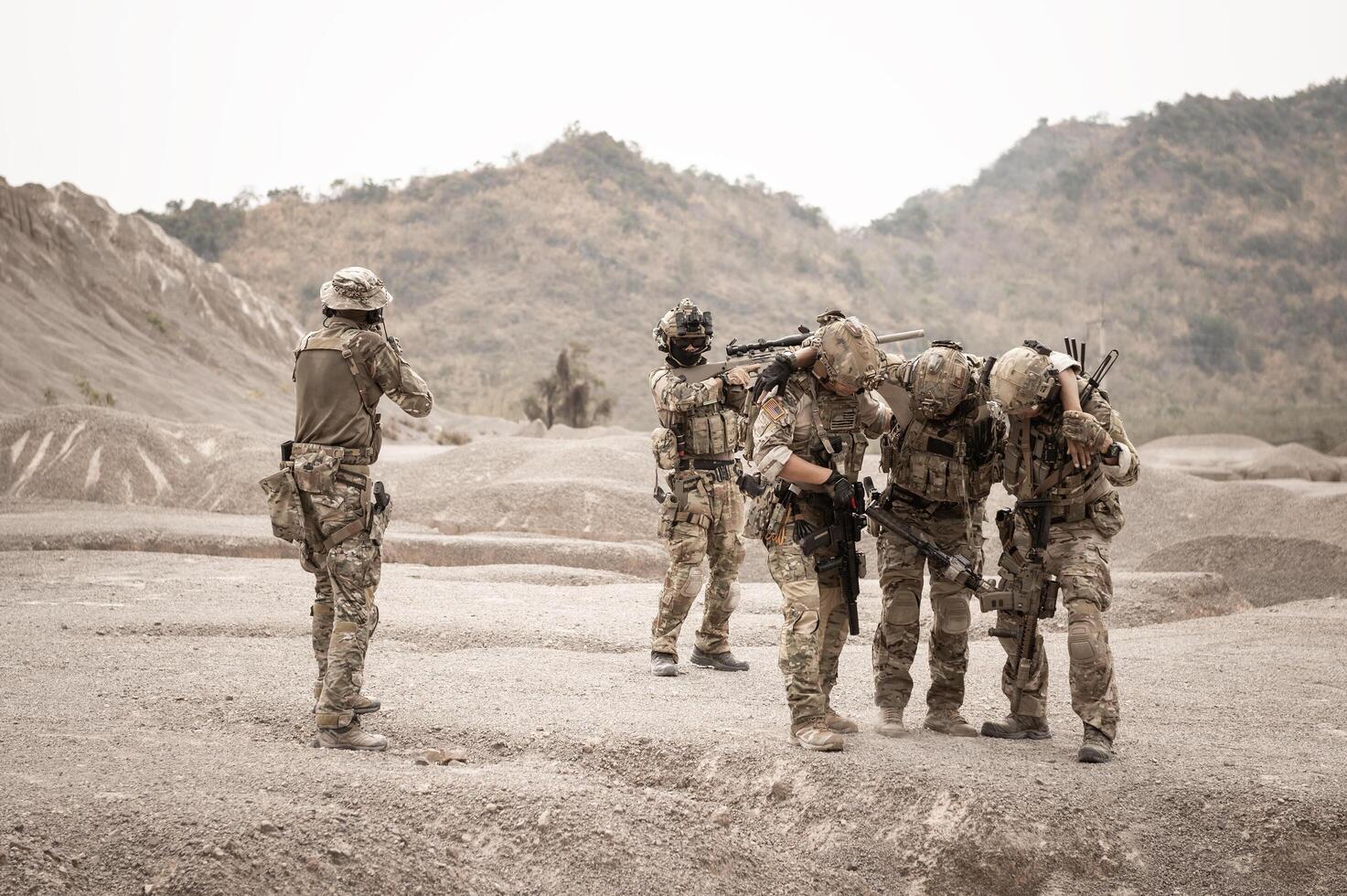 Soldiers in camouflage uniforms aiming with their riflesready to fire during military operation in the desert soldiers training in a military operation photo