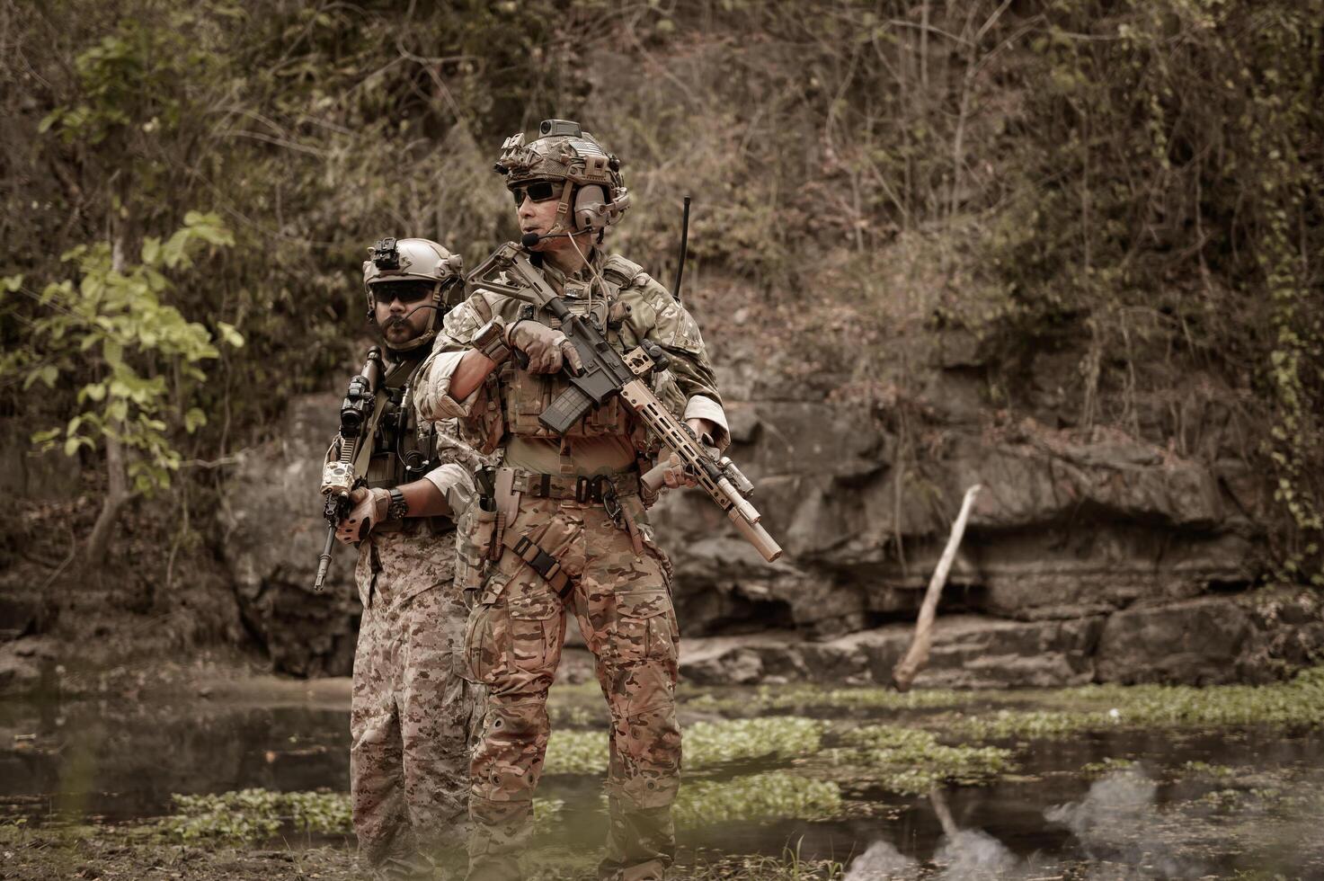 Soldiers in camouflage uniforms aiming with their riflesready to fire during Military Operation in the forest soldiers training in a military operation photo
