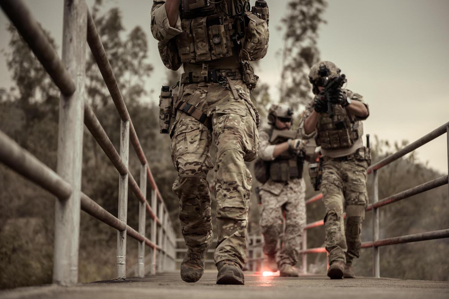 Soldiers in camouflage uniforms aiming with their riflesready to fire during Military Operation in the forest soldiers training in a military operation photo