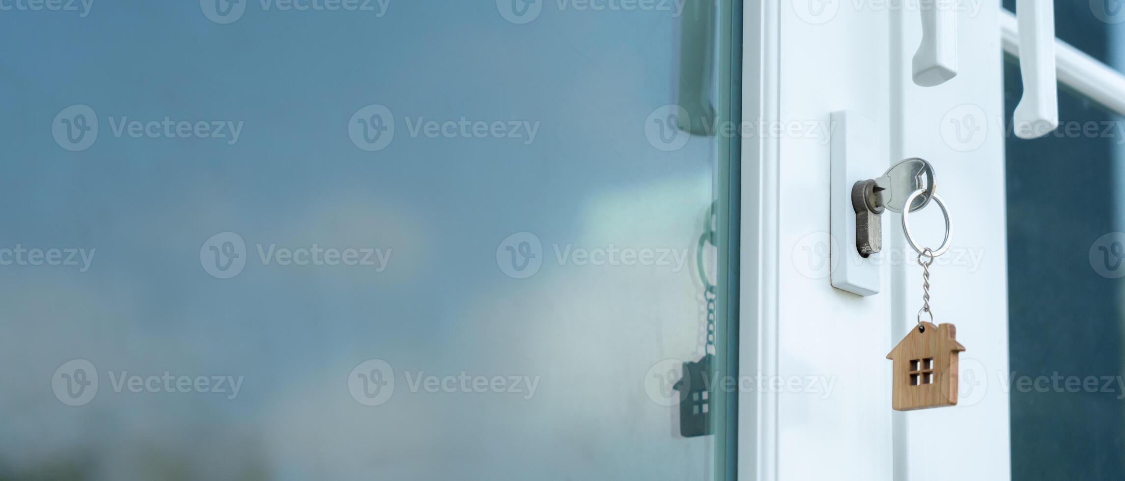 Landlord key for unlocking house is plugged into the door. Second hand house for rent and sale. keychain is blowing in the wind. mortgage for new home, buy, sell, renovate, investment, owner, estate photo