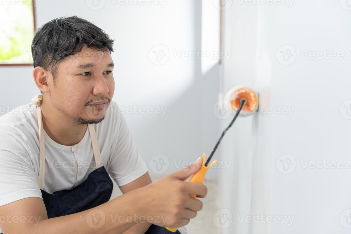 painter man, brush in hand for products to restore and paint the wall, indoor the building site of a house, wall during painting, renovation, painting, contractor, Architect, construction worker photo