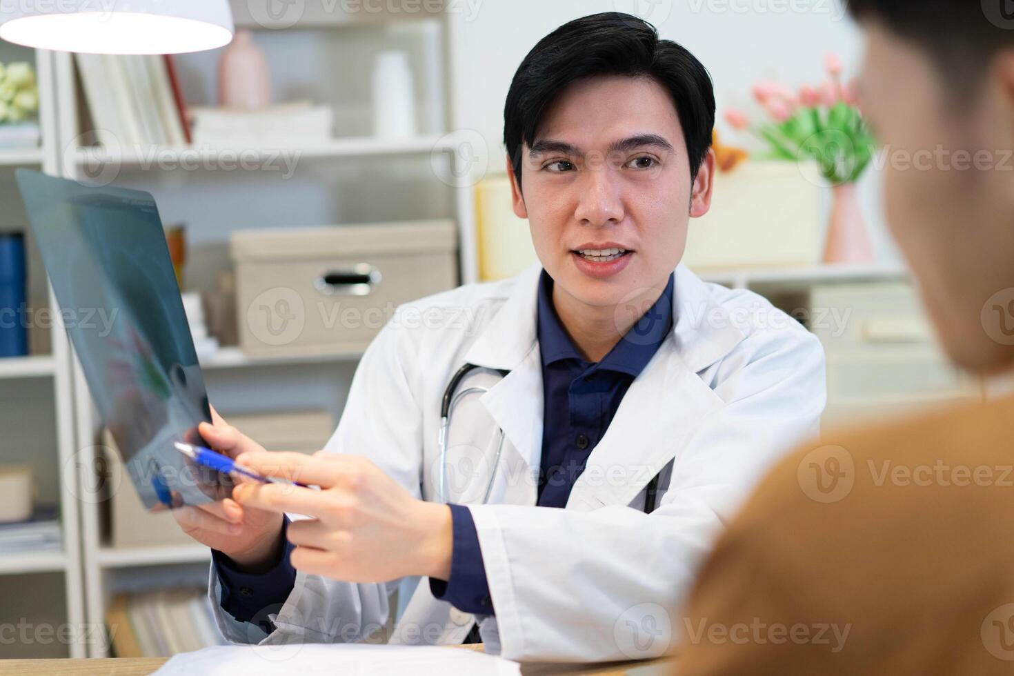 Photo of young Asian male doctor working at office