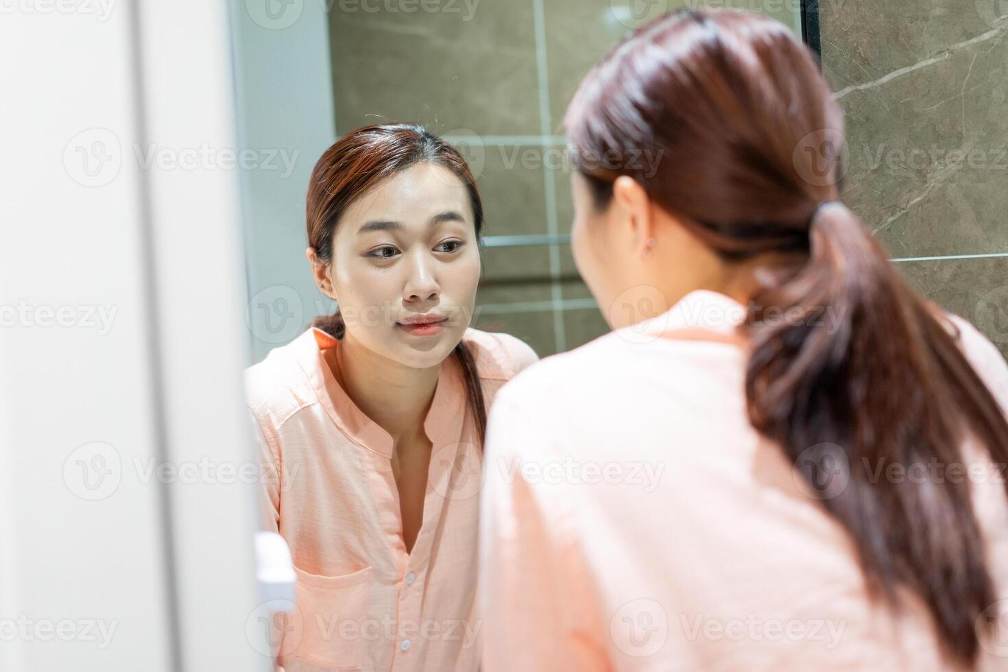 Photo of young Asian woman in bathroom