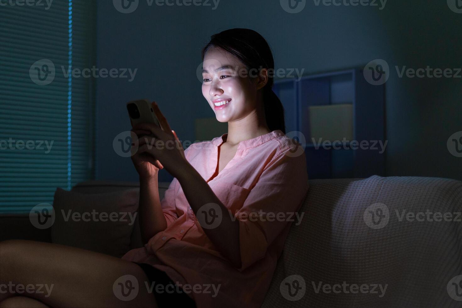 Young Asian woman using phone in the dark at night photo